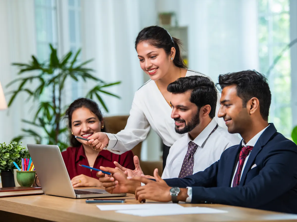 A smiling team discussing work around a laptop